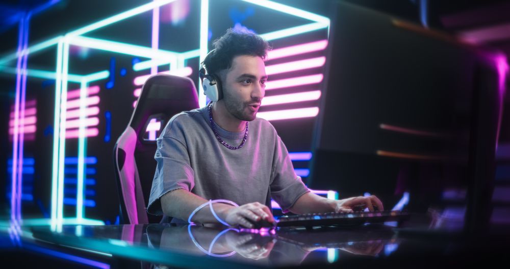 Young Man in a Futuristic Neon Room Playing Action Video Games on a Computer.