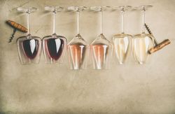 Glasses of wine laying on grey background with corkscrew, copy space