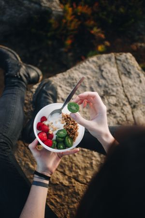 Healthy yogurt & fruit bowl enjoyed by woman outside