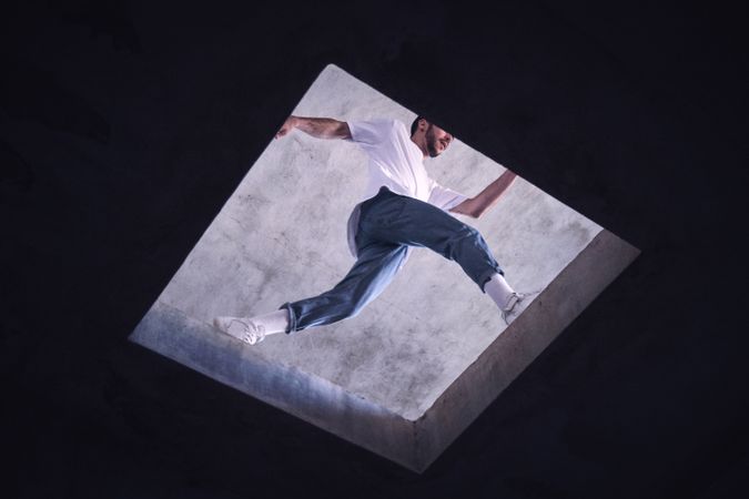 Unrecognizable man jumping near floor opening