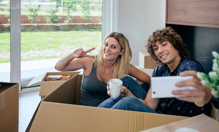 Couple making selfie sitting inside moving box