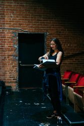 Female director standing with script in the front of the theater