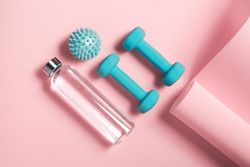 Top view of colorful weights, yoga mat and water