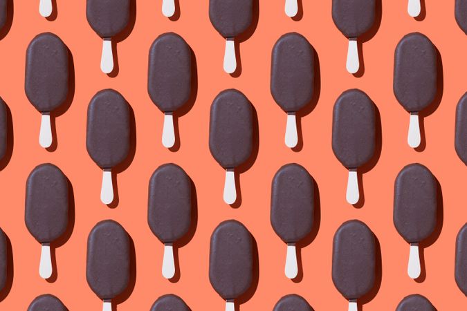 Chocolate popsicle in neat order on orange background