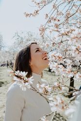 Young happy woman between trees in garden