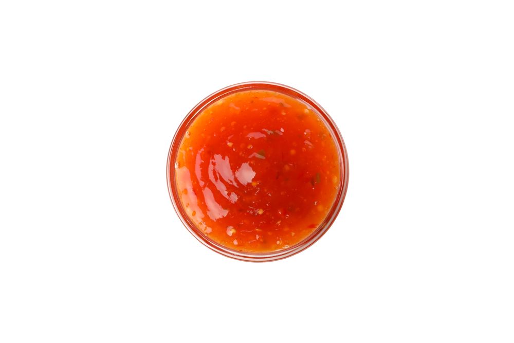 Bowl with tasty chilli sauce isolated on plain background