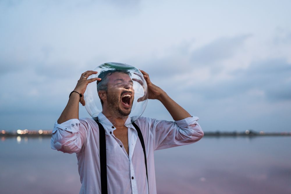 Distressed man with fish tank on head screaming