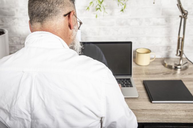 Rear view of middle aged man working on his laptop