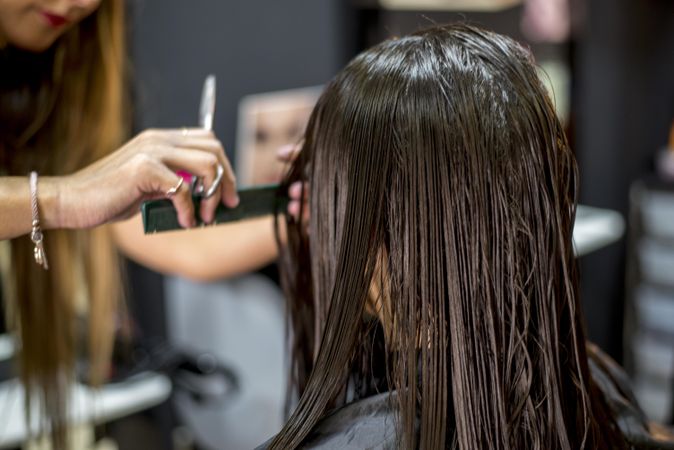 Brunette woman with wet hair sitting in hair dresser’s having a hair cut