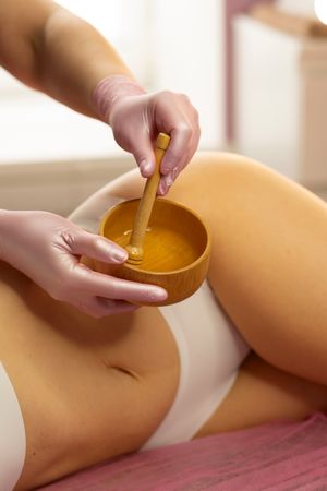 Spa therapist prepares honey mixture in wooden bowl