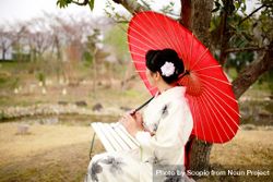 Woman in light and red floral kimono holding red umbrella 0LJoE4
