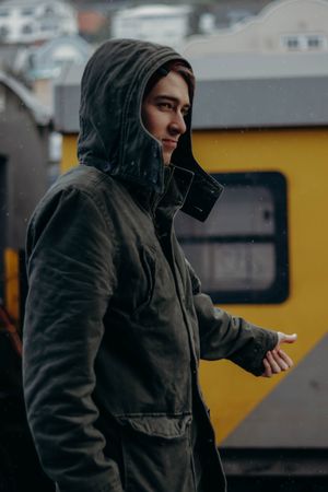 Man in hoodie standing near yellow bus