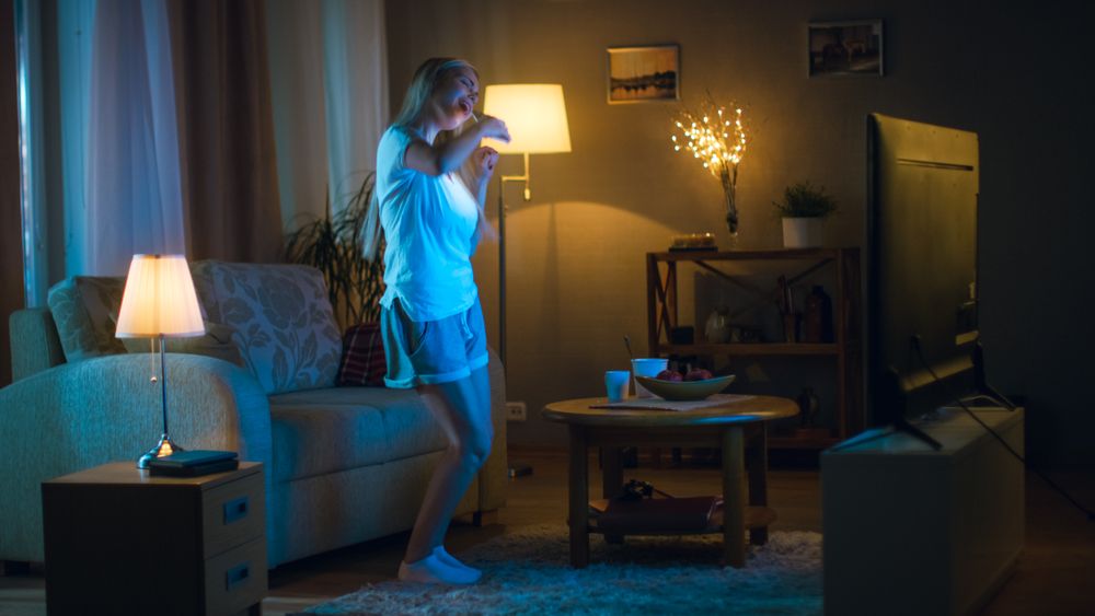 In the Evening Beautiful Woman Happily Dances in Her Living Room while Watching TV