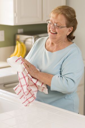 Older Adult Woman Drying Bowl At Sink in Kitchen