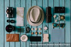 Mix of travel items; hat, camera, map, compass, seashells, arranged on blue background 48dGK4