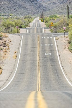 Asphalt road at scenic mountain valley and power line