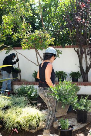 Female contractor working with potted plants in a garden