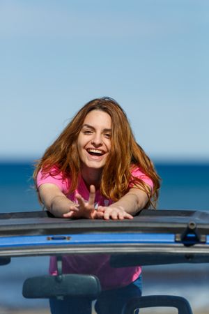 Smiling woman leaning on roof of car