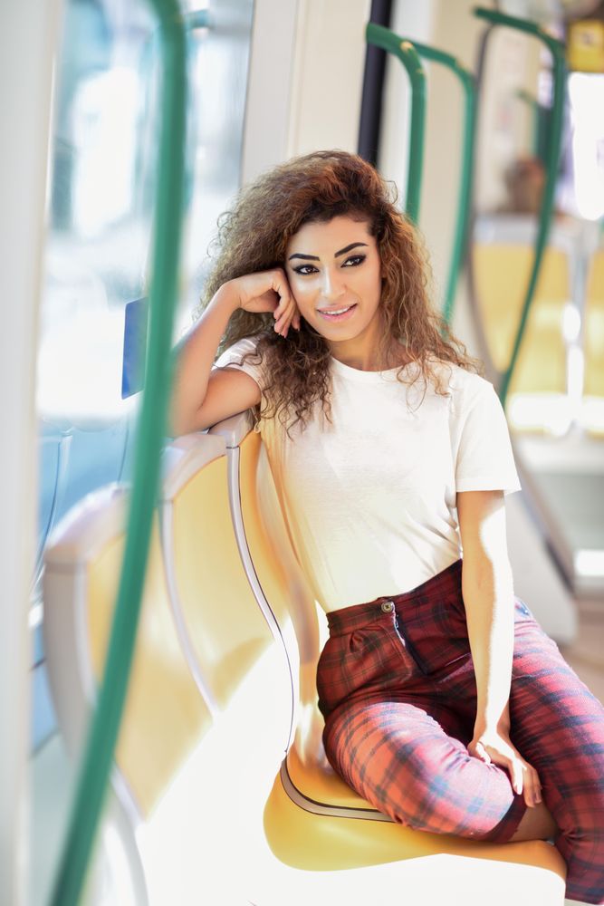 Portrait of Arab woman sitting in train carriage resting head on hand
