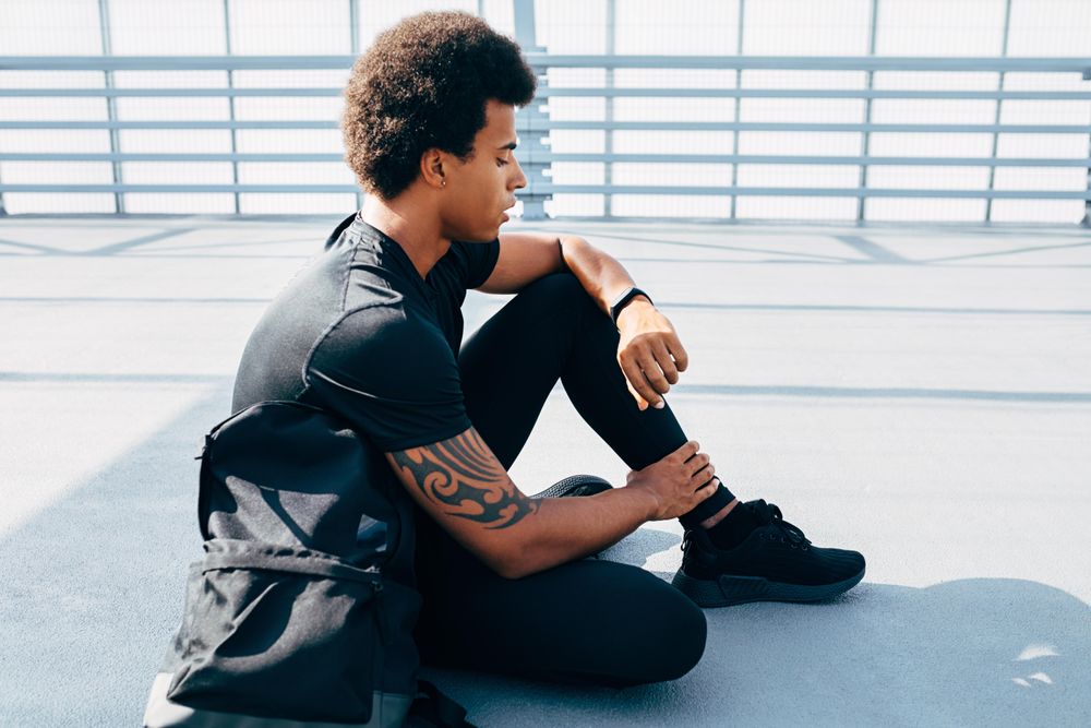 Sportsman sitting on bridge looking at activity tracking device