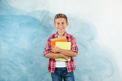 Boy with copybooks against color background, space for text