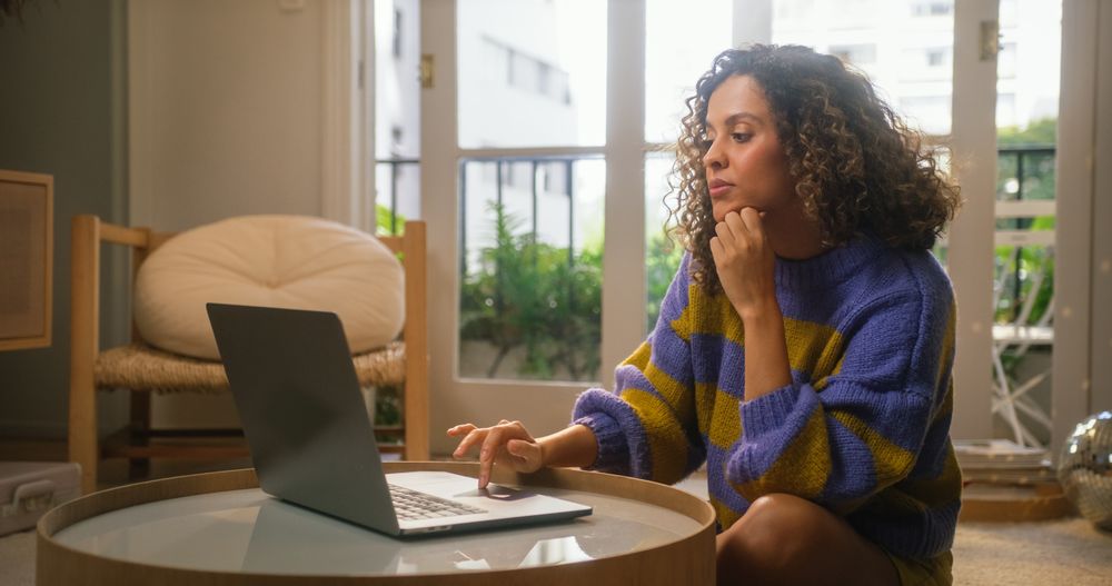 Portrait of Serious Young Woman Working from Home on Laptop Computer in Sunny Cozy Apartment.
