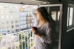 Young thoughtful woman with cup looking at street