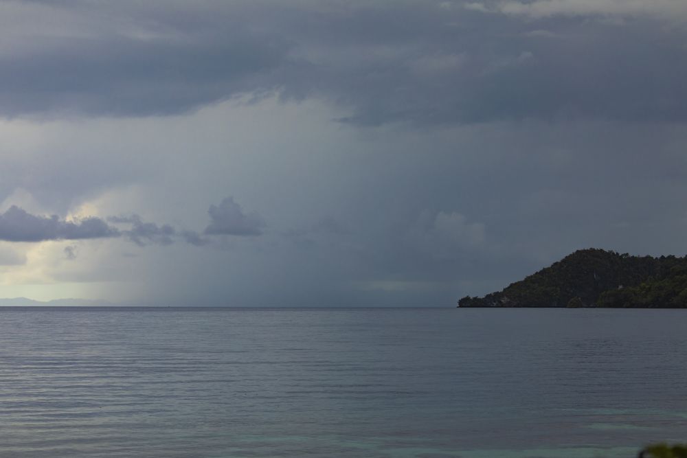 Storm clouds on a rainy day, over the horizon and Friwin islands in the distance, Raja Ampat Islands