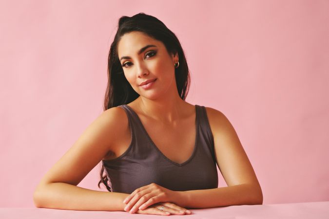 Smiling Hispanic woman looking at camera and sitting in pink room