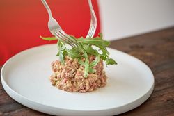 Unrecognizable person decorating steak tartar on plate