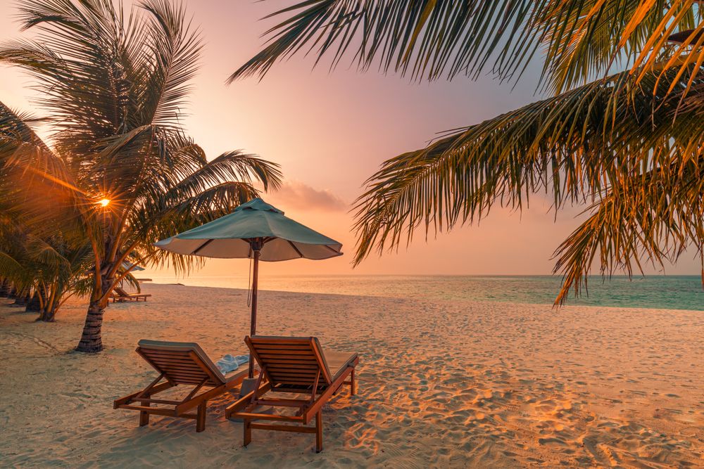 Two reclining lounge chairs on a beach, landscape
