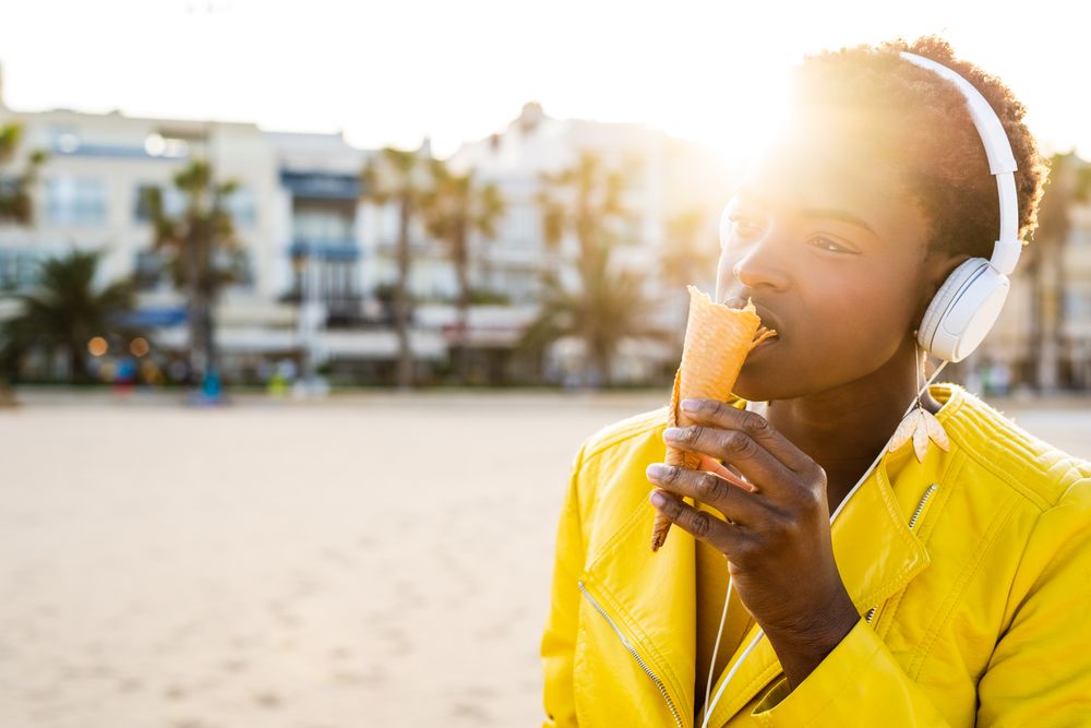 Cool female eating ice cream on beach
