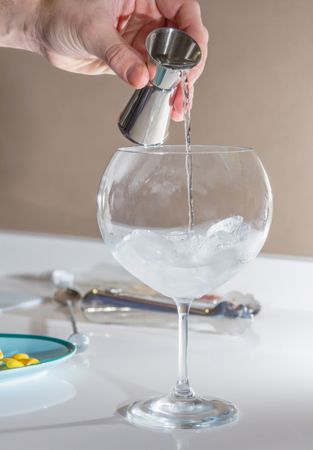 Barman pouring drink to prepare gin tonic cocktail