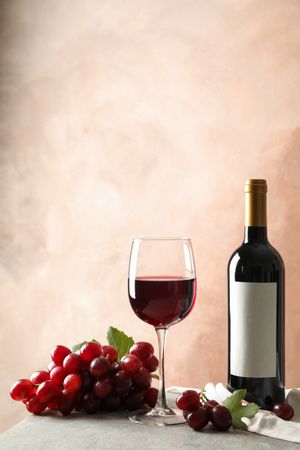 Grape, bottle and glass with wine on grey background, space for text