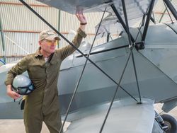 Confident pilot beside retro plane in hangar