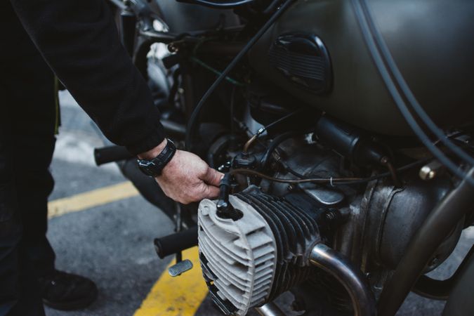 Crop man repairing motorcycle engine