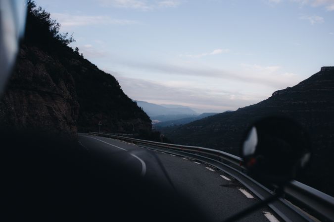 Rear view of motorcycle rider traveling out of the mountains