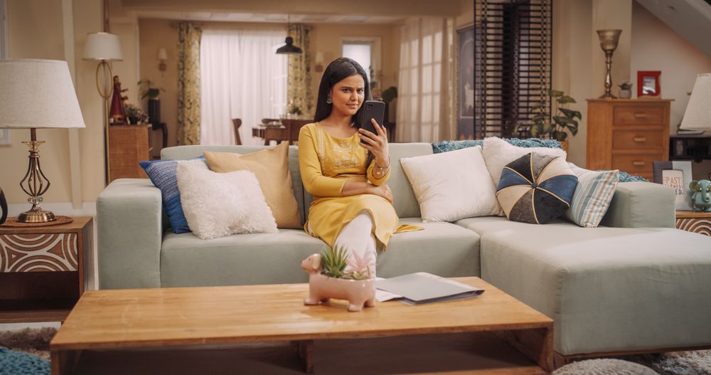 Portrait of a Young Indian Woman Looking at her Smartphone, Reading the News in her Fancy Home.