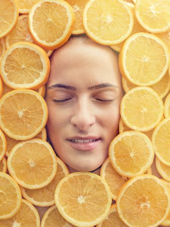 Portrait of beautiful woman among fresh oranges