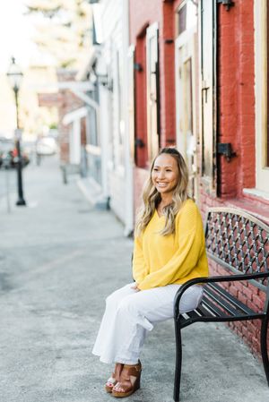 Woman in yellow shirt sitting on metal bench outdoor