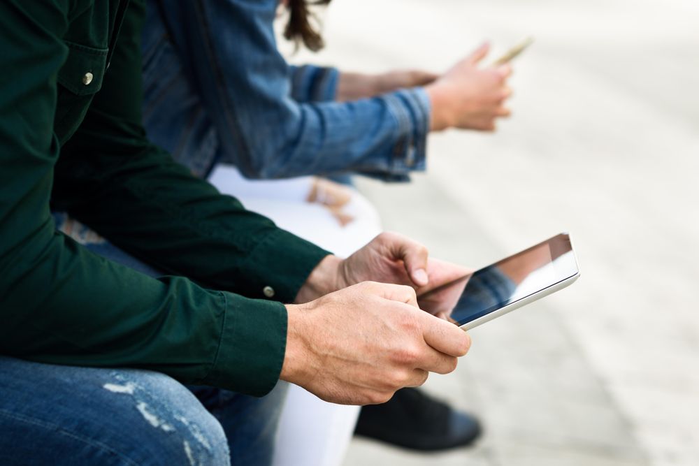 Close up of people using smart phones sitting outside