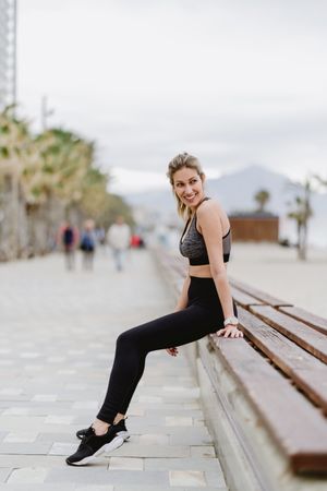 Sportswoman resting in a bench at sandy beach