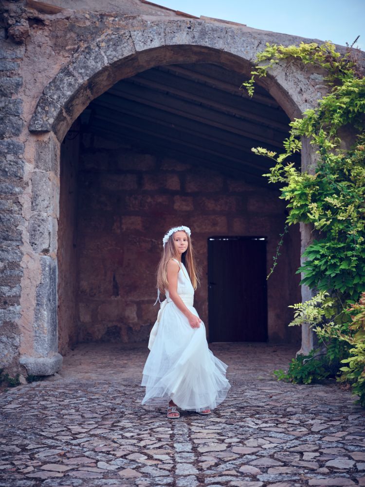 Pretty young girl in wedding dress standing at ancient building