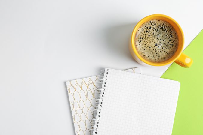 Cup of coffee with copybooks on color background, top view