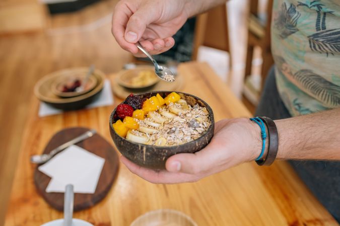 Unrecognizable chef adding seeds to exotic fruit and cereal breakfast bowl in cooking master class