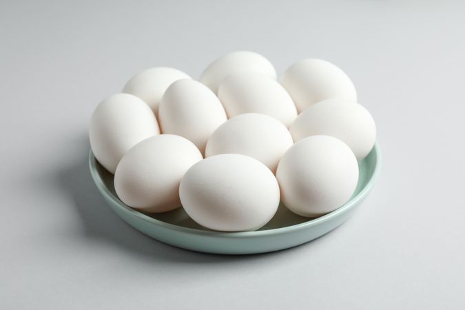 Chicken eggs in plate on gray background, space for text