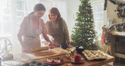 Portrait of Adult Woman Preparing Gingerbread for Christmas While her Mature Mother is Helping.