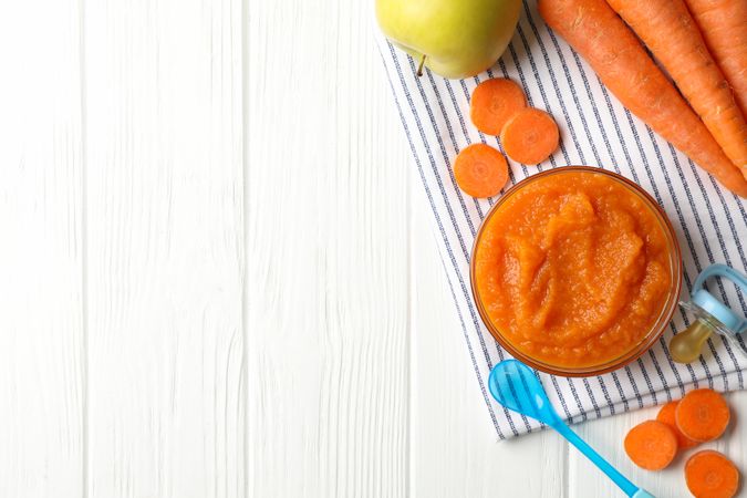 Composition with carrot puree on wooden background. Baby food