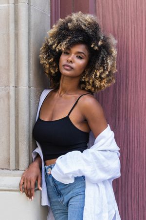 Stylish Black woman standing near colorful door