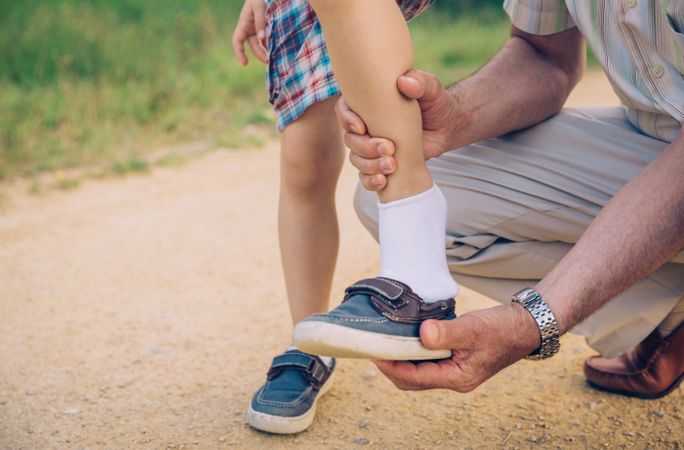 Grandfather putting shoe to his grandson outdoors